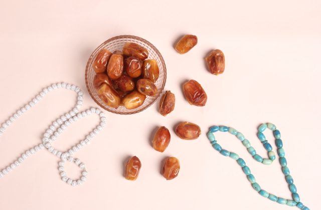 a glass bowl filled with nuts next to a beaded necklace