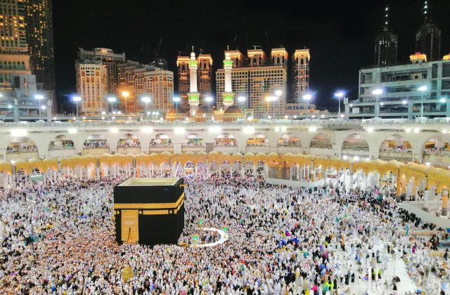 Aerial view of the Kaaba surrounded by pilgrims in Makkah at night, showcasing a religious gathering.
