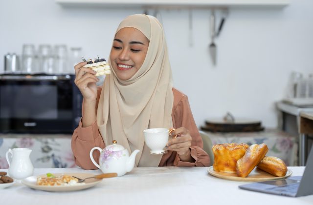 young muslim woman in hijab eating sweets, bread, waffles, cakes, healthy food menu and happily drin